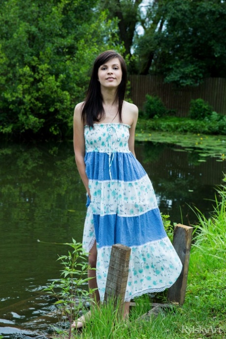 Dark haired teen Zelda lifts up a long dress to expose her nice pussy by water 98425438