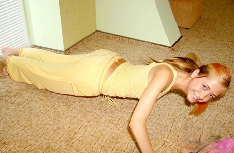 Flexible young girl stretches out on carpeted flooring while fully clothed 80205265