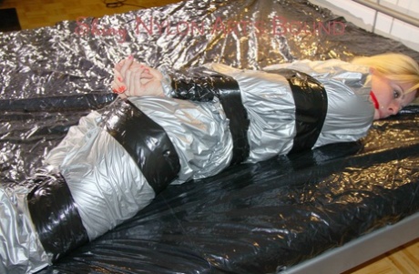 White girl with blonde hair is left gagged and tied up in silver rainwear 79204781