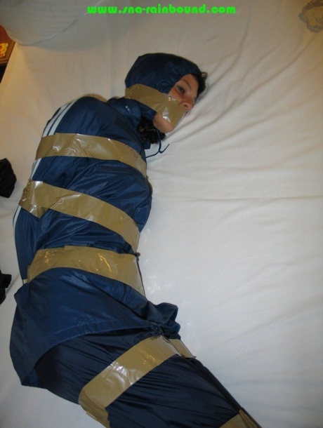 Caucasian female is left tied up and gagged while wearing nylon rain wear 86657799