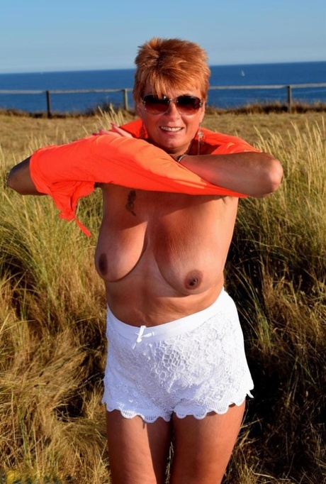 Older redhead Dimonty uncovers her natural tits not too far from the ocean 65067745