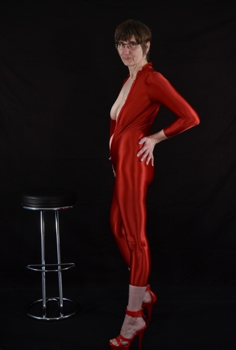 Brunette lady Hot MILF unzips from a shiny red catsuit in glasses and heels 35552602